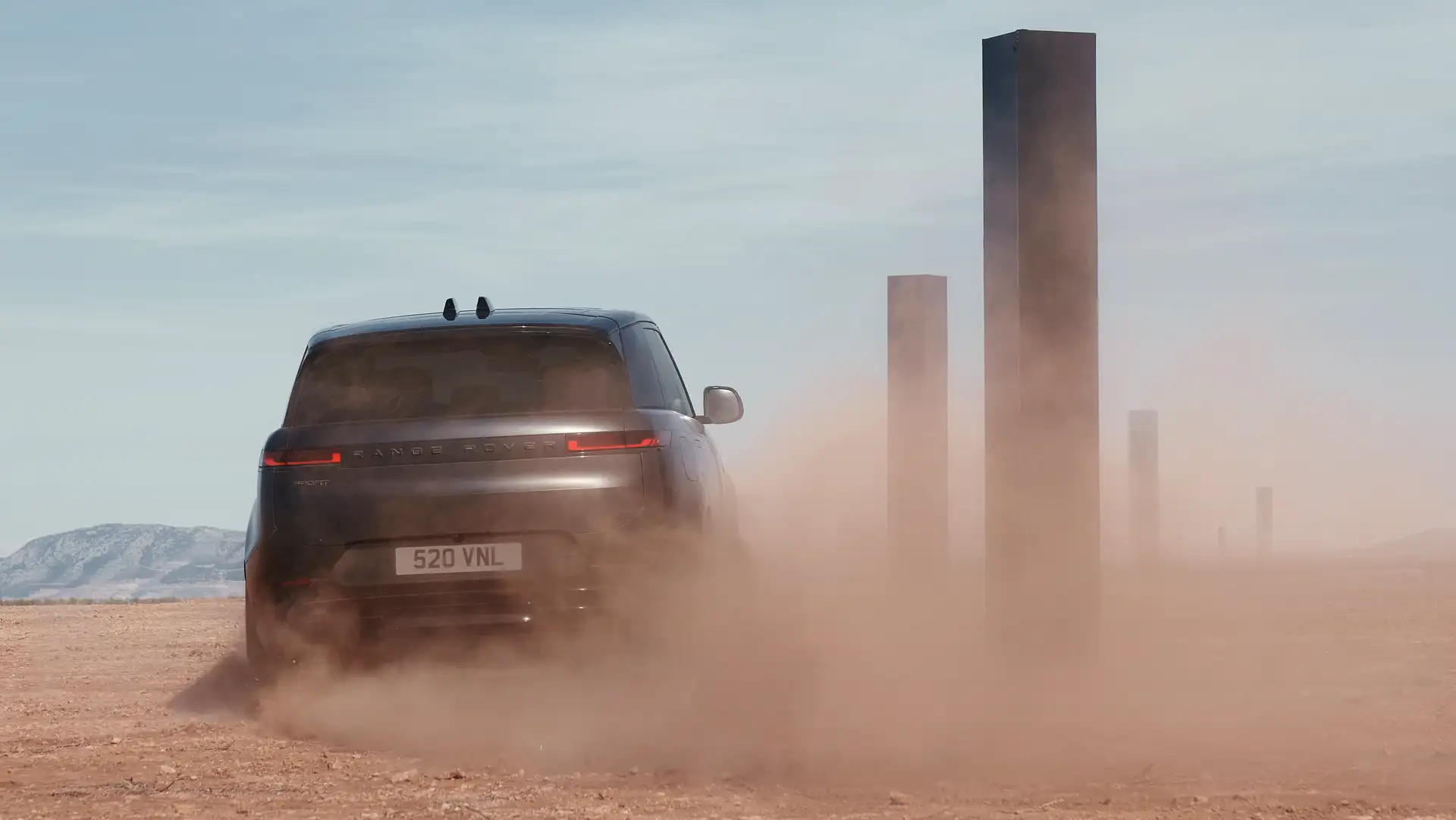 Der Range Rover Sport in der Heckansicht auf einer verstaubten Straße. 